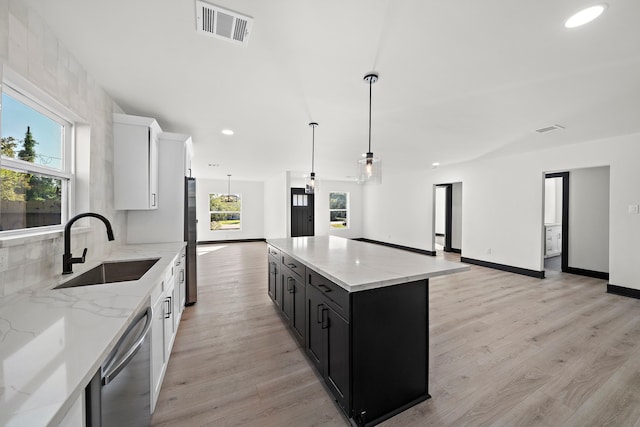 kitchen featuring white cabinets, sink, decorative light fixtures, light hardwood / wood-style floors, and stainless steel appliances