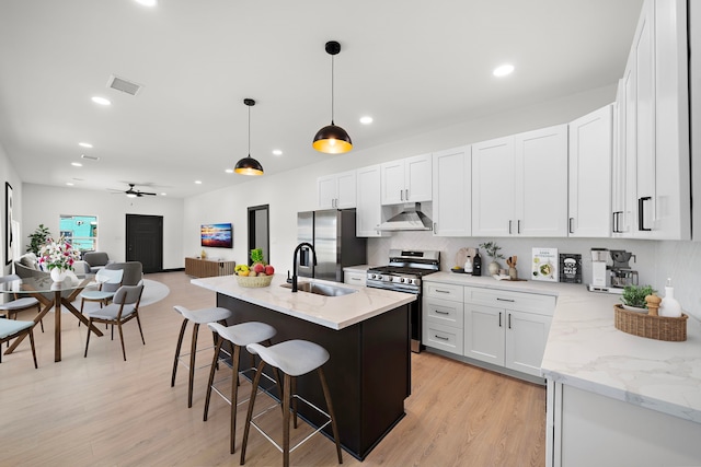 kitchen with white cabinets, ceiling fan, light wood-type flooring, appliances with stainless steel finishes, and decorative light fixtures