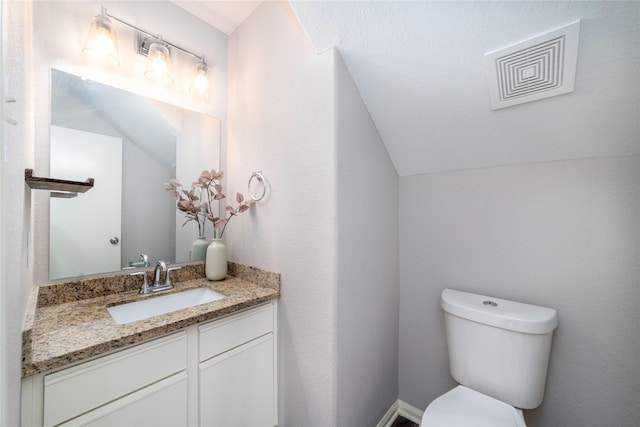 bathroom with vanity, vaulted ceiling, and toilet