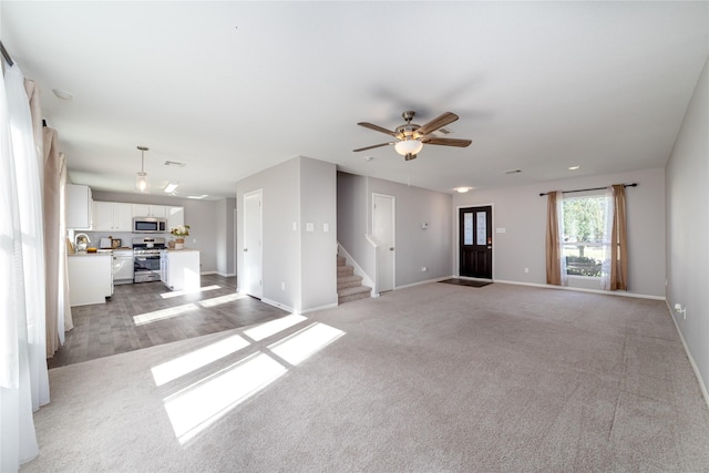 unfurnished living room featuring ceiling fan and light carpet