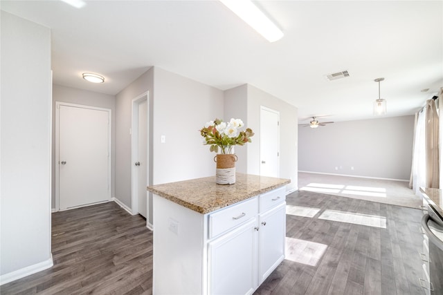 kitchen featuring a center island, dark hardwood / wood-style floors, ceiling fan, light stone counters, and white cabinetry