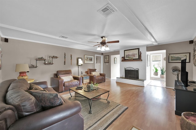 living room featuring a fireplace, light hardwood / wood-style flooring, ceiling fan, and ornamental molding