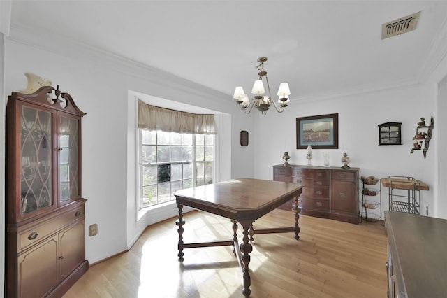 dining room featuring light hardwood / wood-style flooring, crown molding, and a notable chandelier