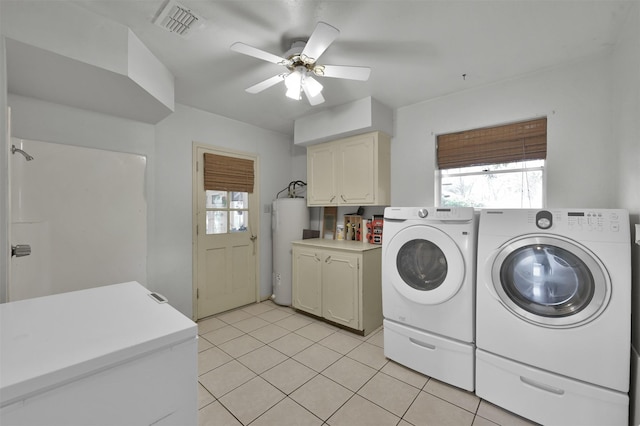 clothes washing area featuring light tile patterned flooring, washing machine and dryer, cabinets, and water heater