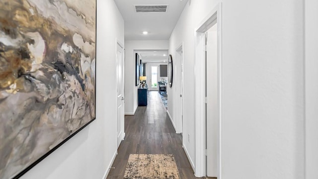 hallway with dark wood-style flooring, visible vents, and baseboards