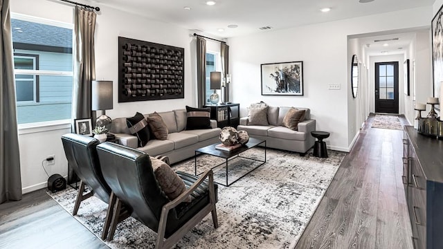 living area with recessed lighting, wood finished floors, visible vents, and baseboards