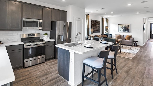 kitchen featuring decorative backsplash, dark wood-style floors, open floor plan, stainless steel appliances, and a sink