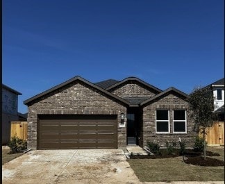 ranch-style house with driveway, brick siding, an attached garage, and fence