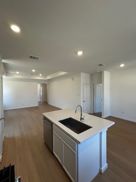 kitchen featuring stainless steel dishwasher, dark wood-style floors, open floor plan, and a sink