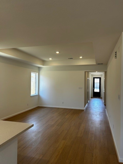 unfurnished room with visible vents, baseboards, a raised ceiling, dark wood-style flooring, and recessed lighting