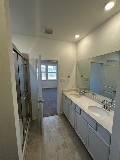 bathroom with visible vents, a sink, and a shower stall