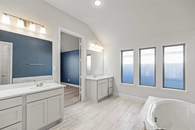 bathroom featuring a bathing tub, vanity, and lofted ceiling