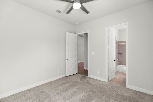 unfurnished bedroom with ensuite bath, ceiling fan, and light colored carpet