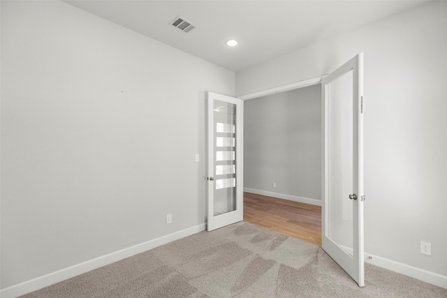 empty room with french doors and light colored carpet