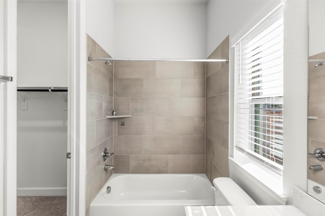 bathroom with toilet and tiled shower / bath