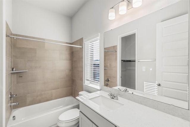 full bathroom featuring vanity, tiled shower / bath combo, and toilet