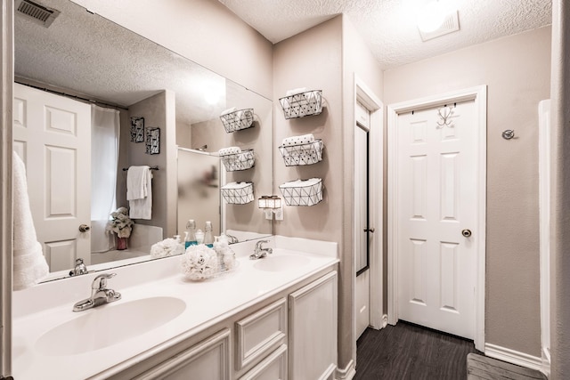 bathroom featuring hardwood / wood-style flooring, vanity, and a textured ceiling