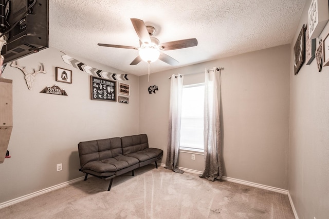 living area with light carpet, ceiling fan, and a textured ceiling