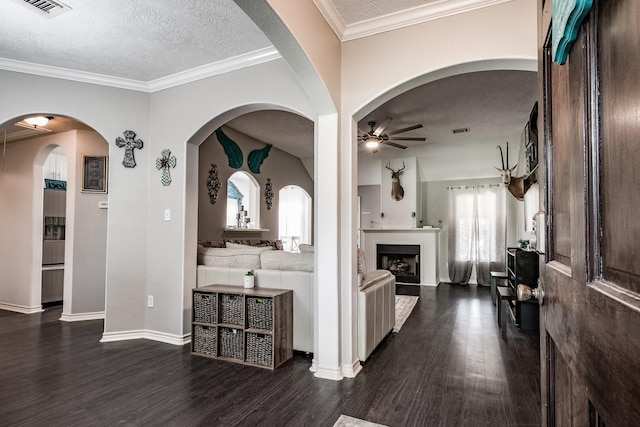 hallway with a textured ceiling, dark hardwood / wood-style flooring, vaulted ceiling, and ornamental molding