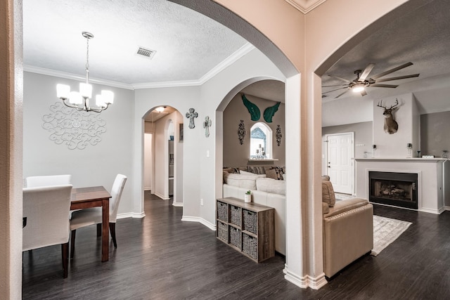 living room featuring ceiling fan with notable chandelier, dark hardwood / wood-style flooring, a textured ceiling, and crown molding