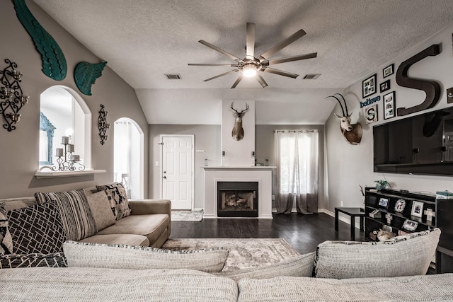 living room featuring dark hardwood / wood-style floors, ceiling fan, a textured ceiling, and vaulted ceiling