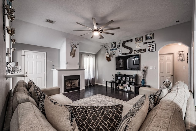 living room with ceiling fan, wood-type flooring, a textured ceiling, and vaulted ceiling