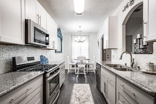 kitchen featuring sink, dark hardwood / wood-style floors, light stone counters, and stainless steel appliances