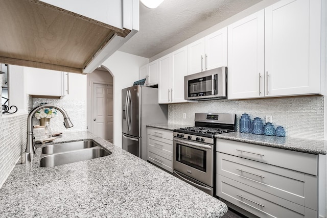 kitchen with white cabinets, appliances with stainless steel finishes, tasteful backsplash, and sink