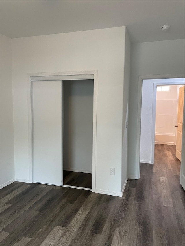 unfurnished bedroom with a closet and dark hardwood / wood-style flooring