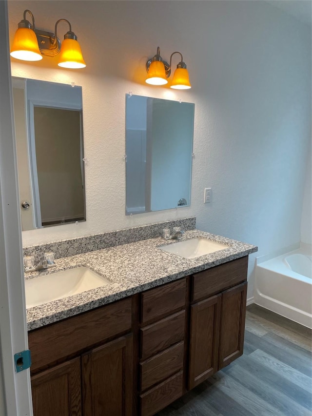 bathroom with vanity, wood-type flooring, and a bath