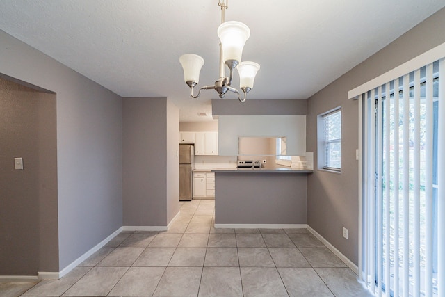 kitchen featuring a notable chandelier, kitchen peninsula, stainless steel fridge, pendant lighting, and white cabinets