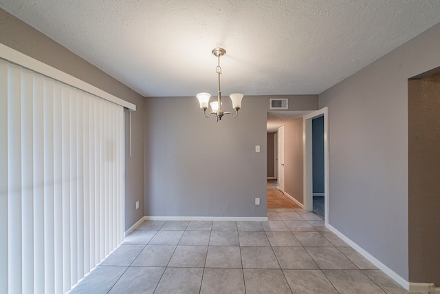 unfurnished dining area featuring a notable chandelier, light tile patterned flooring, and a textured ceiling