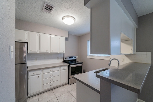 kitchen with kitchen peninsula, appliances with stainless steel finishes, backsplash, sink, and white cabinetry