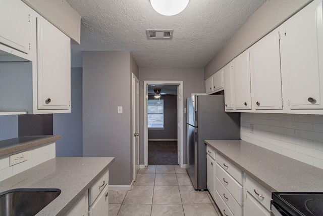 kitchen featuring white cabinets, decorative backsplash, light tile patterned flooring, and a textured ceiling