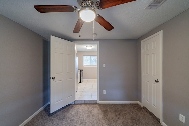 unfurnished bedroom featuring ceiling fan, light colored carpet, and a textured ceiling