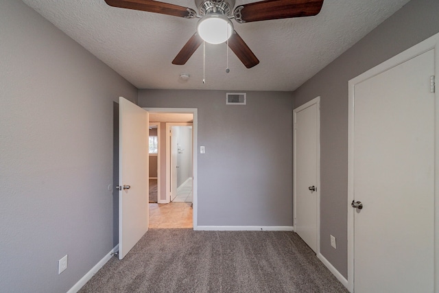 unfurnished bedroom with ceiling fan, light colored carpet, and a textured ceiling