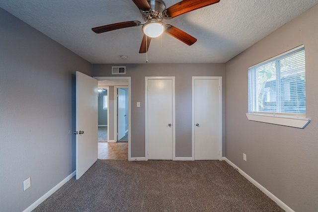 unfurnished bedroom featuring ceiling fan, carpet floors, and a textured ceiling