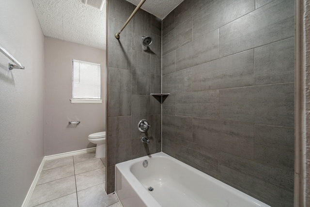 bathroom with toilet, tile patterned flooring, a textured ceiling, and tiled shower / bath