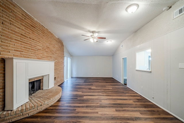 unfurnished living room featuring a textured ceiling, vaulted ceiling, ceiling fan, a fireplace, and dark hardwood / wood-style floors