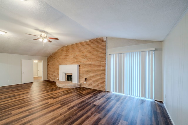 unfurnished living room with a textured ceiling, a large fireplace, vaulted ceiling, and dark wood-type flooring