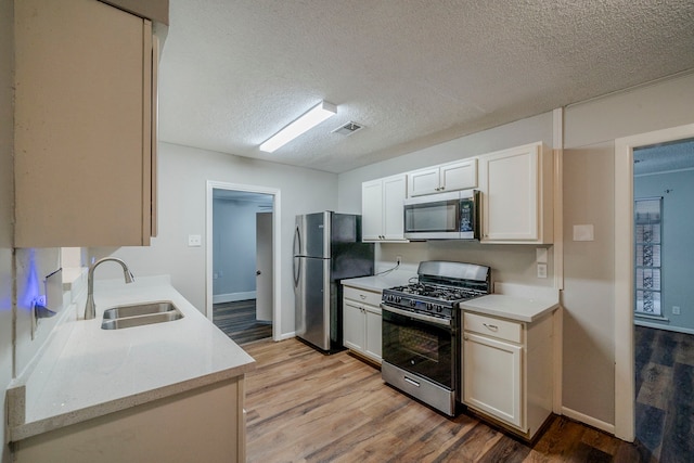 kitchen with appliances with stainless steel finishes, light hardwood / wood-style floors, and sink