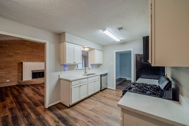 kitchen with brick wall, sink, wood-type flooring, dishwasher, and black gas stove