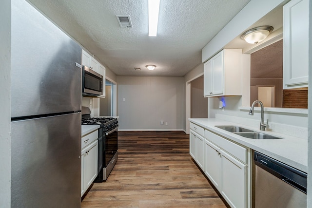 kitchen with white cabinetry, sink, stainless steel appliances, a textured ceiling, and light wood-type flooring