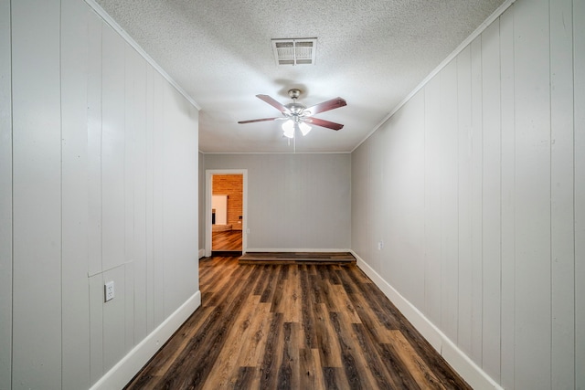 empty room with ceiling fan, wood walls, dark hardwood / wood-style flooring, and ornamental molding