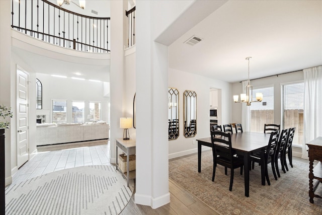 dining area featuring a high ceiling, light hardwood / wood-style floors, and an inviting chandelier