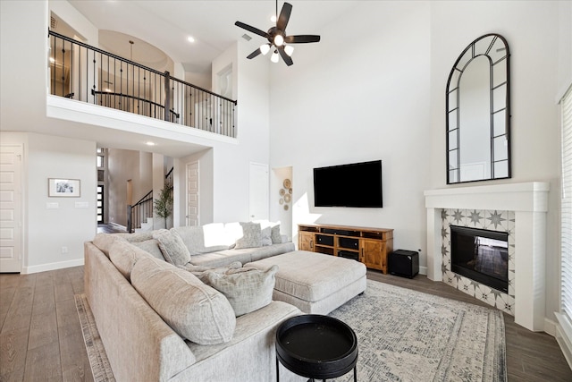 living room with a fireplace, dark hardwood / wood-style flooring, and a towering ceiling