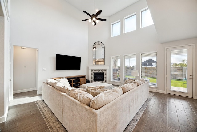 living room with a towering ceiling, dark hardwood / wood-style floors, and ceiling fan