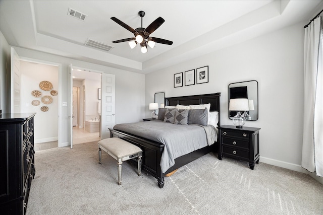 bedroom with light colored carpet, a raised ceiling, ceiling fan, and ensuite bathroom