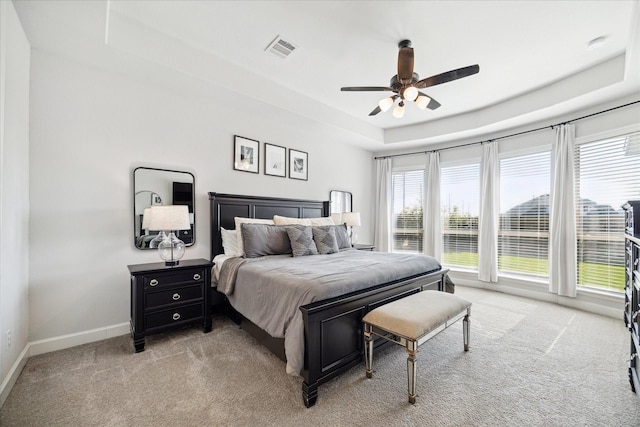 carpeted bedroom featuring ceiling fan and a raised ceiling