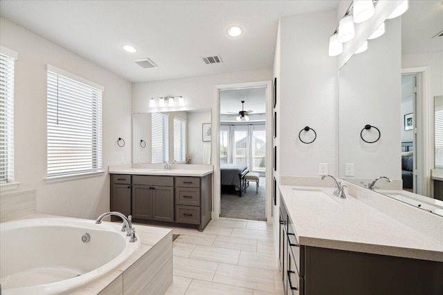 bathroom featuring a relaxing tiled tub, plenty of natural light, ceiling fan, and vanity